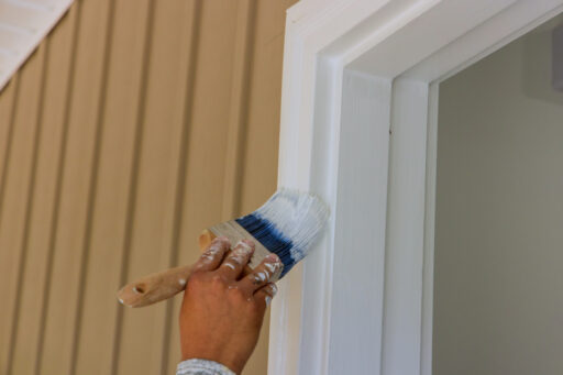 The carpenter applies paintbrush to wooden moldings and door trim for the purpose of painting them